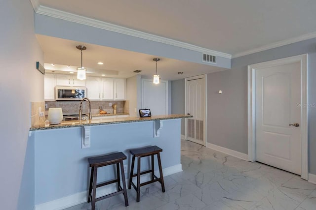 kitchen with a kitchen bar, kitchen peninsula, light stone countertops, white cabinets, and hanging light fixtures