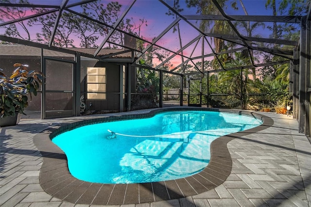 pool at dusk with a lanai and a patio area