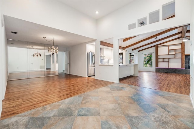 unfurnished living room featuring beam ceiling, wood-type flooring, high vaulted ceiling, and an inviting chandelier