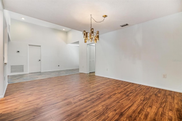 unfurnished room featuring an inviting chandelier and hardwood / wood-style floors