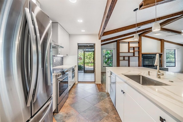 kitchen featuring appliances with stainless steel finishes, decorative light fixtures, lofted ceiling with beams, white cabinetry, and sink