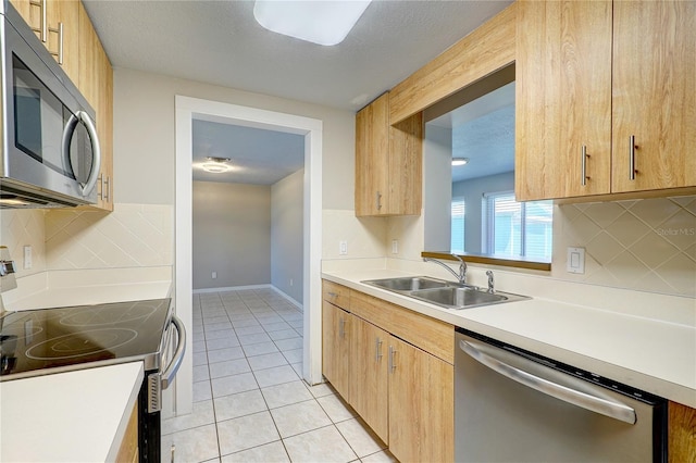 kitchen with light tile patterned floors, sink, appliances with stainless steel finishes, and tasteful backsplash