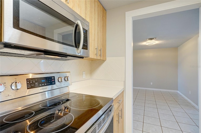 kitchen featuring light brown cabinets, light tile patterned floors, backsplash, and appliances with stainless steel finishes