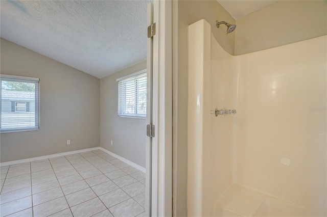 bathroom featuring tile patterned floors, a shower, a textured ceiling, and vaulted ceiling