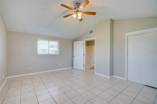 unfurnished bedroom with vaulted ceiling, ceiling fan, light tile patterned floors, a textured ceiling, and a closet