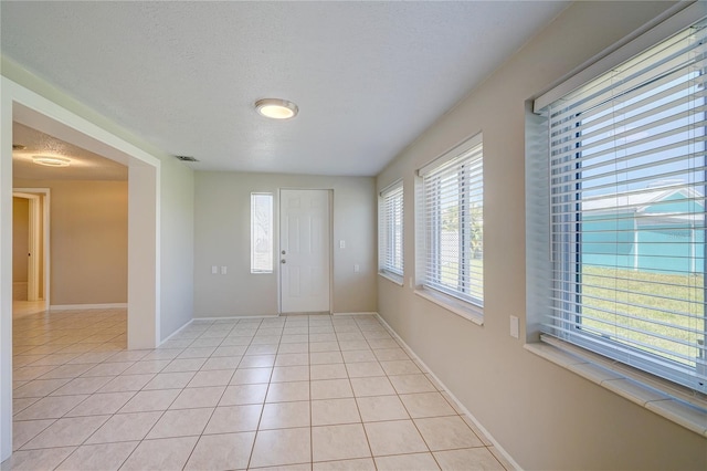 foyer entrance featuring a textured ceiling and light tile patterned flooring