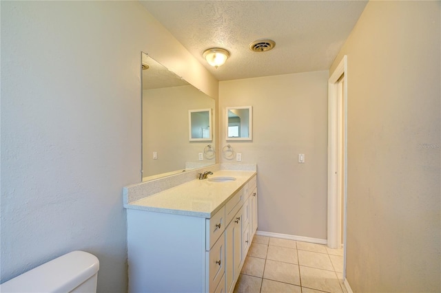 bathroom with tile patterned flooring, vanity, toilet, and a textured ceiling