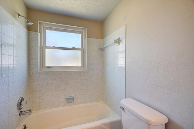 bathroom featuring a textured ceiling, tiled shower / bath combo, and toilet