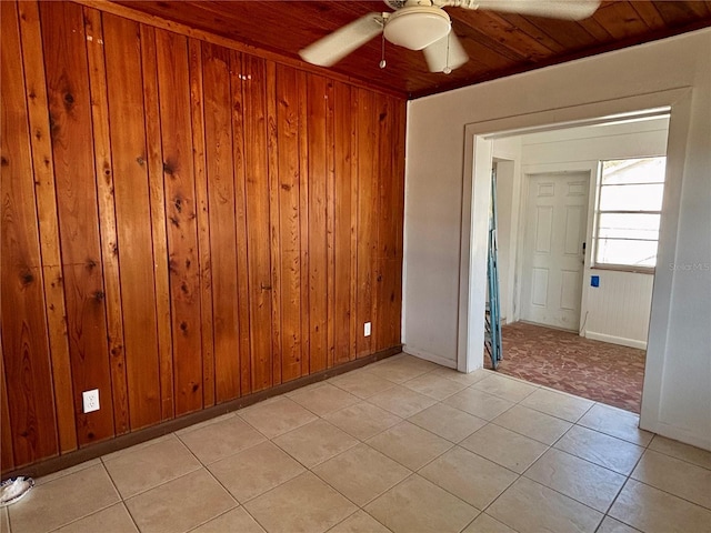 tiled empty room featuring wood ceiling, ceiling fan, and wood walls