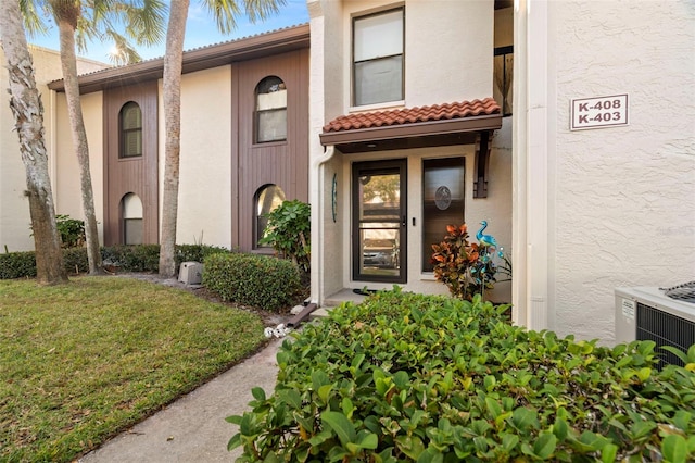 view of exterior entry featuring central AC and a yard