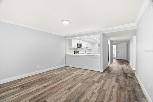 unfurnished living room featuring crown molding, hardwood / wood-style floors, and sink