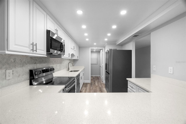 kitchen with white cabinets, stainless steel appliances, decorative backsplash, sink, and ornamental molding