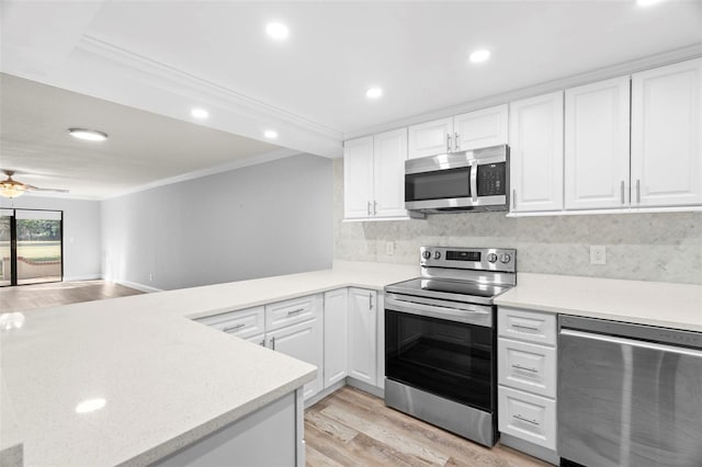 kitchen featuring white cabinetry, appliances with stainless steel finishes, kitchen peninsula, and tasteful backsplash