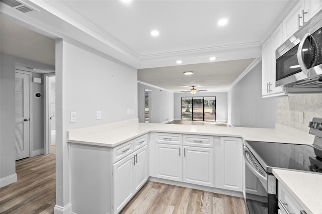 kitchen featuring kitchen peninsula, ceiling fan, appliances with stainless steel finishes, light wood-type flooring, and white cabinets