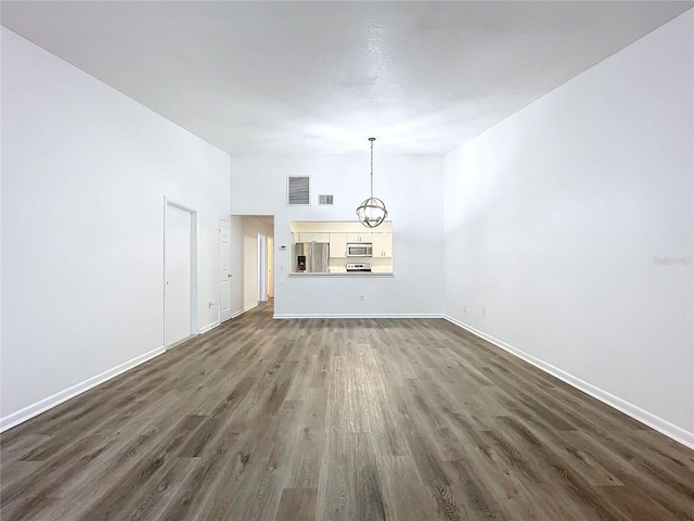 unfurnished living room with dark hardwood / wood-style flooring and an inviting chandelier