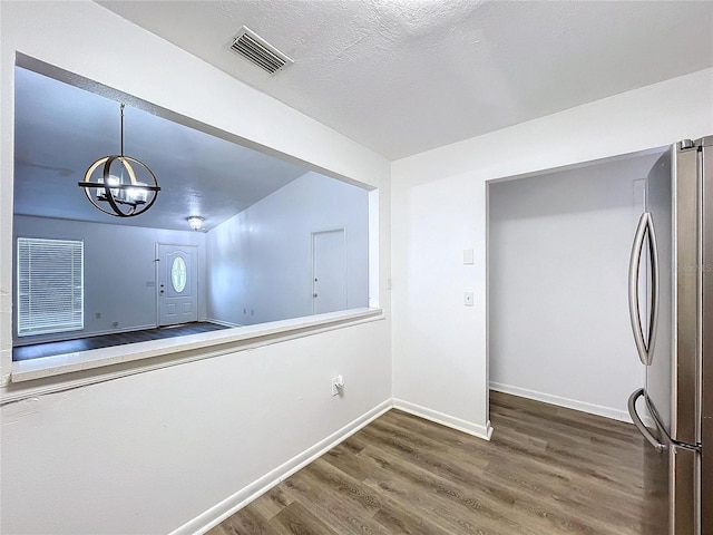 interior space with a textured ceiling, a notable chandelier, and dark wood-type flooring