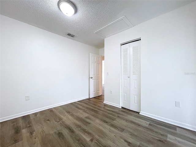 unfurnished bedroom featuring a textured ceiling, a closet, and dark hardwood / wood-style floors