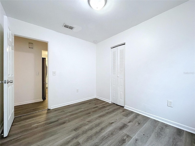 unfurnished bedroom featuring dark wood-type flooring and a closet