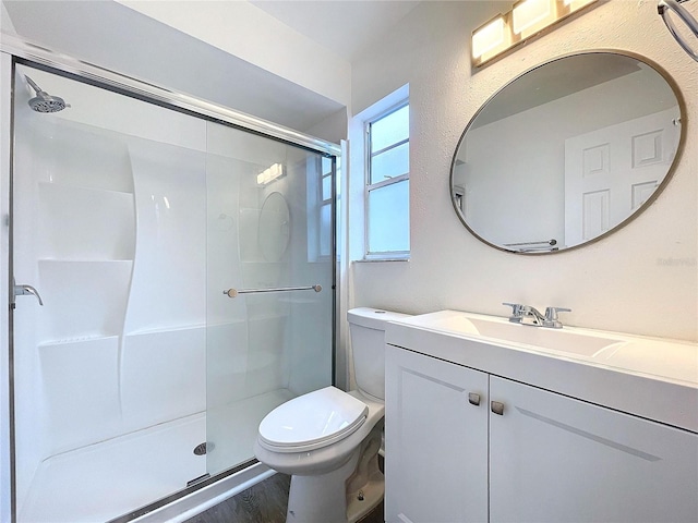 bathroom with hardwood / wood-style flooring, vanity, toilet, and walk in shower