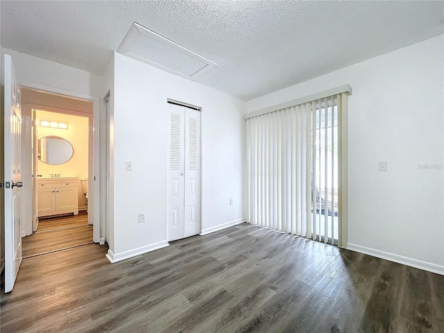 unfurnished bedroom with a textured ceiling, a closet, and dark wood-type flooring