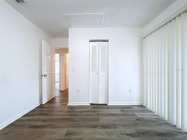 unfurnished bedroom with dark hardwood / wood-style floors, a textured ceiling, and a closet