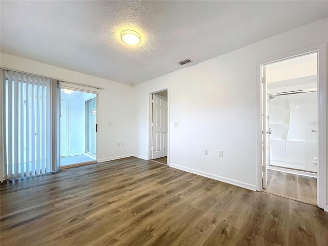 spare room with a textured ceiling and dark hardwood / wood-style floors