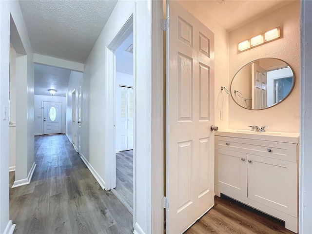 corridor featuring a textured ceiling, dark wood-type flooring, and sink