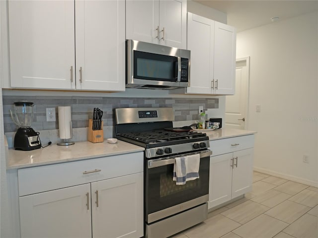 kitchen featuring light stone countertops, tasteful backsplash, light tile patterned flooring, white cabinetry, and stainless steel appliances