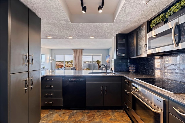 kitchen featuring sink, backsplash, dark stone counters, a textured ceiling, and appliances with stainless steel finishes