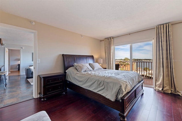 bedroom featuring a textured ceiling, access to outside, and dark wood-type flooring