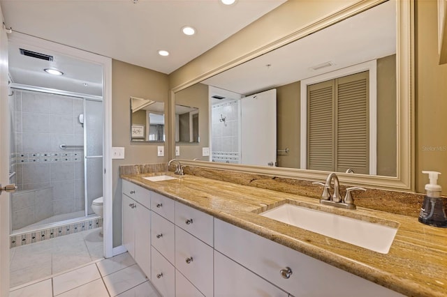 bathroom featuring tile patterned floors, vanity, toilet, and a shower with shower door