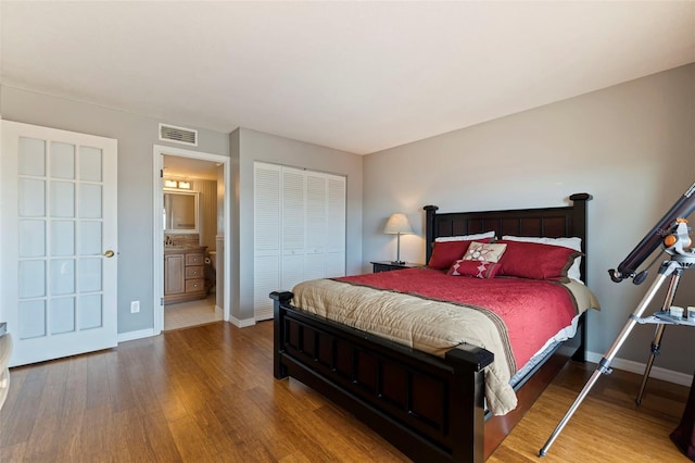 bedroom with hardwood / wood-style flooring, connected bathroom, and a closet