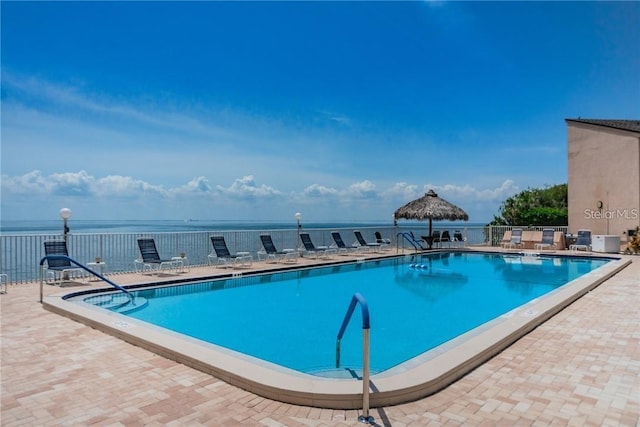 view of pool featuring a water view and a patio area