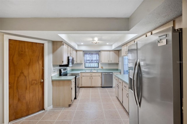 kitchen featuring sink, stainless steel appliances, a raised ceiling, light brown cabinetry, and light tile patterned floors