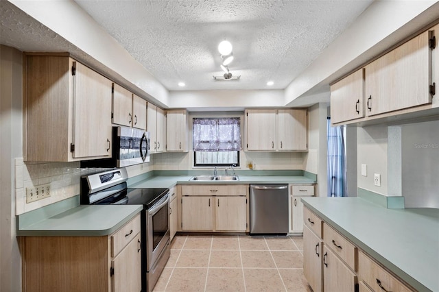 kitchen featuring a textured ceiling, light brown cabinets, sink, and appliances with stainless steel finishes