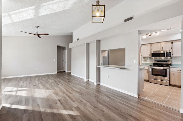 unfurnished living room with ceiling fan, light hardwood / wood-style flooring, a textured ceiling, and vaulted ceiling