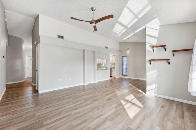 unfurnished living room featuring ceiling fan, high vaulted ceiling, light hardwood / wood-style floors, and a textured ceiling