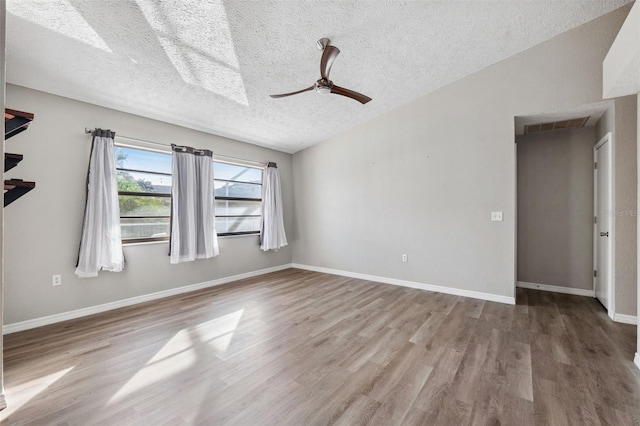 spare room with vaulted ceiling, ceiling fan, light hardwood / wood-style floors, and a textured ceiling