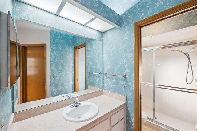 bathroom featuring vanity, toilet, and a shower with shower door