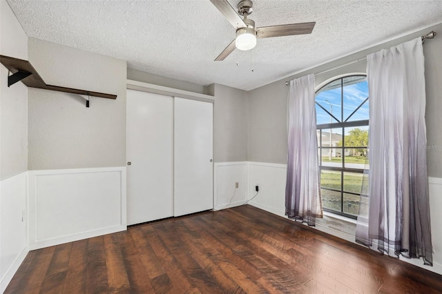 unfurnished bedroom featuring a closet, ceiling fan, dark hardwood / wood-style flooring, and a textured ceiling