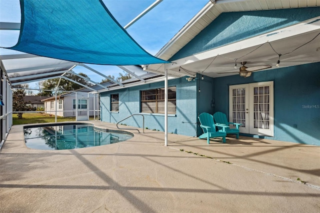 view of swimming pool featuring glass enclosure, ceiling fan, and a patio area