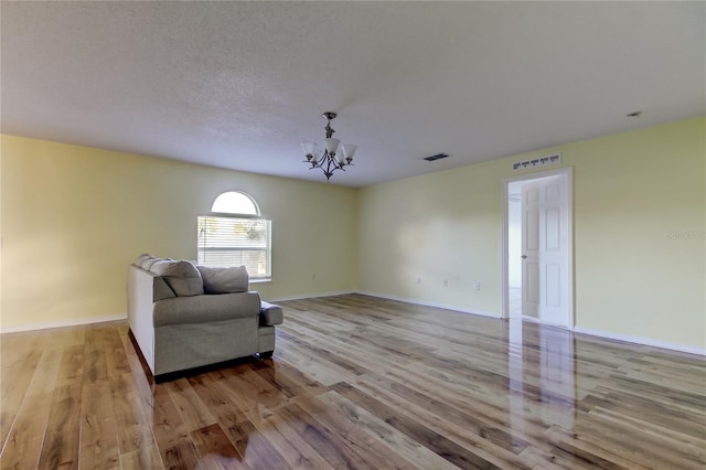 living area featuring a textured ceiling, light hardwood / wood-style floors, and an inviting chandelier