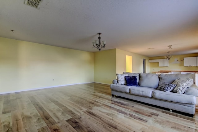 unfurnished living room featuring a chandelier and light wood-type flooring