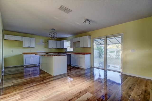 kitchen with a kitchen island, butcher block counters, white cabinetry, and a wealth of natural light