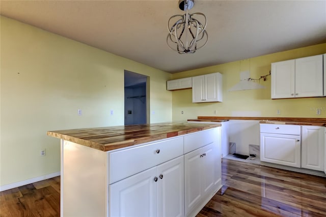 kitchen with butcher block counters, hanging light fixtures, a kitchen island, white cabinets, and hardwood / wood-style flooring