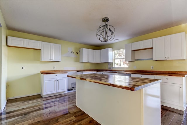 kitchen featuring wood counters, white cabinets, hanging light fixtures, a kitchen island, and wood-type flooring