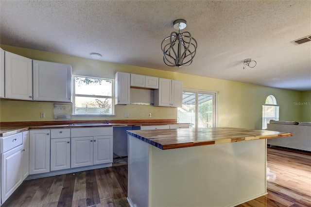 kitchen featuring wood counters, decorative light fixtures, plenty of natural light, dark hardwood / wood-style flooring, and white cabinetry