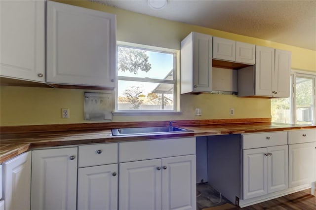 kitchen featuring white cabinets, butcher block countertops, dark hardwood / wood-style floors, and sink