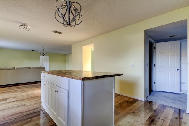 kitchen with white cabinetry, wooden counters, a notable chandelier, decorative light fixtures, and a kitchen island