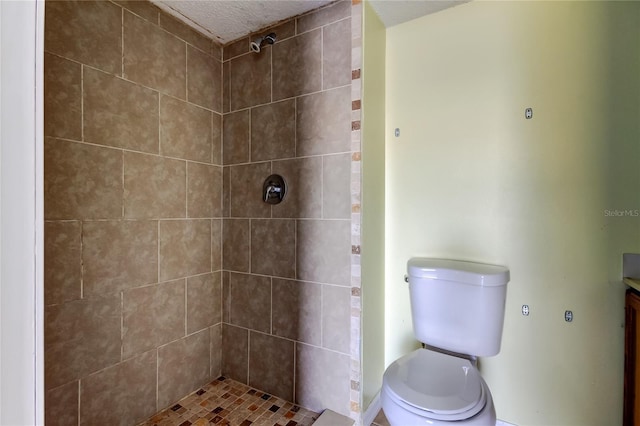 bathroom featuring a tile shower, vanity, and toilet